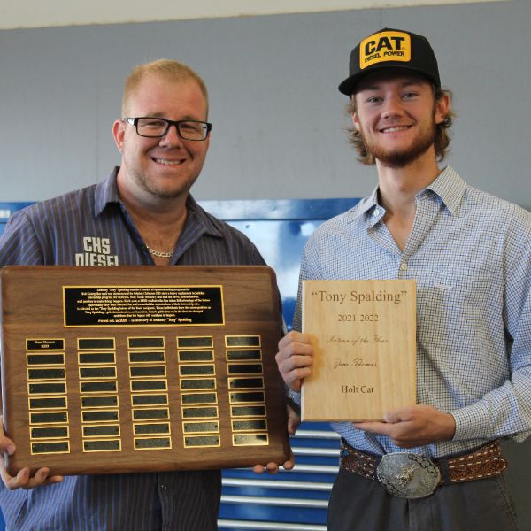  Picture of a man and a student in a ballcap hold plaques